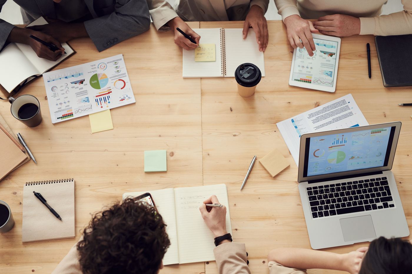 Time multidisciplinar analisando gráficos e relatórios durante uma reunião de trabalho.