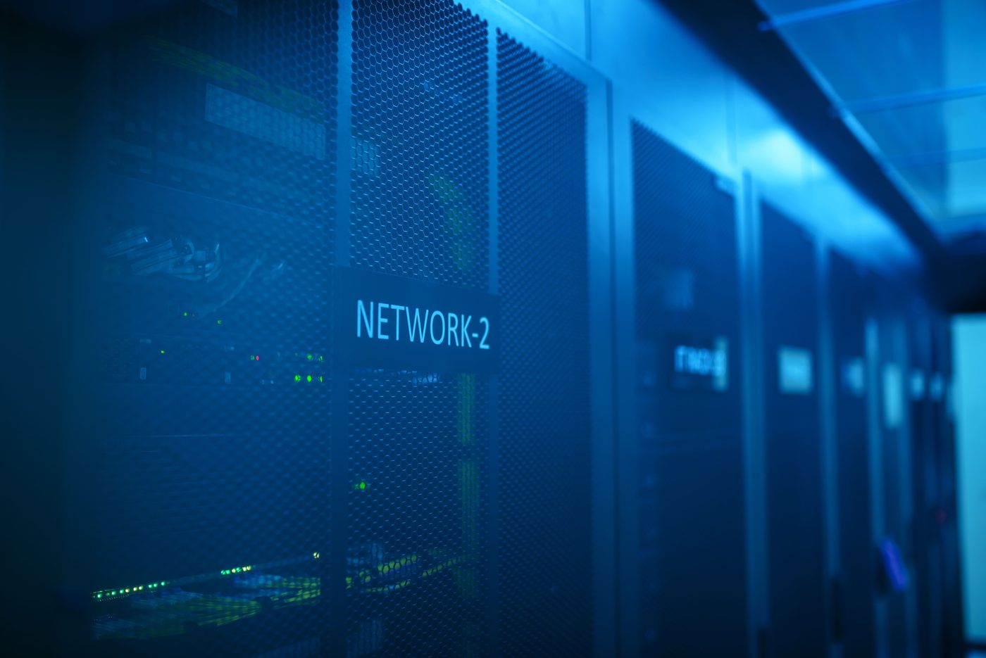 Rack de rede com iluminação azul em uma sala de servidores, representando infraestrutura híbrida.
