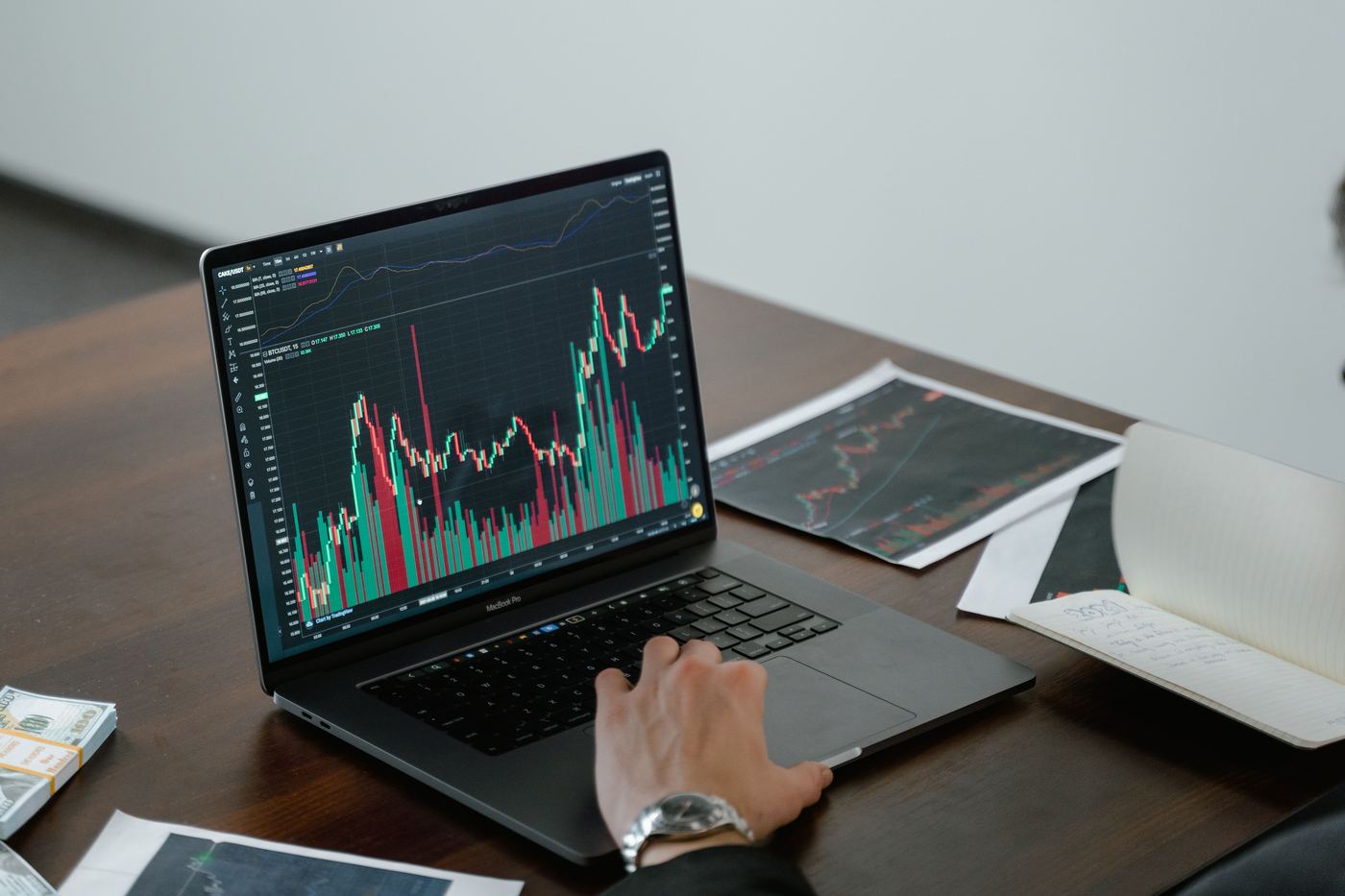 Pessoa analisando gráficos e indicadores financeiros em um notebook.